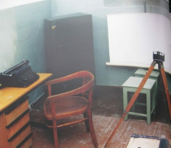 En esta habitación se le quitaba ropa al arrestado como cinturones, cordones de los zapatos y cualquier otro objeto... también se le cortaban todos los botones de la camisa, etc. Se les realizaban 2 fotos, una de perfil y otro de cara. También se les tomaban las huellas dactilares.